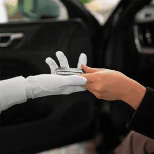 a woman handing a key to a man wearing white gloves in a car, and the woman is using valet parking service in Houston