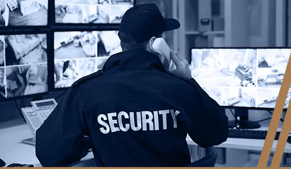 A security guard is in front of several monitors.